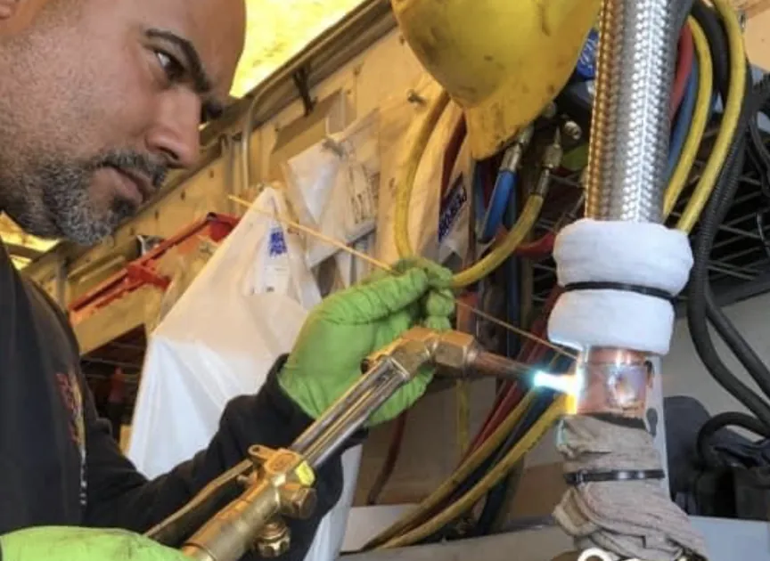 Technician brazing refrigeration lines during an emergency reefer repair