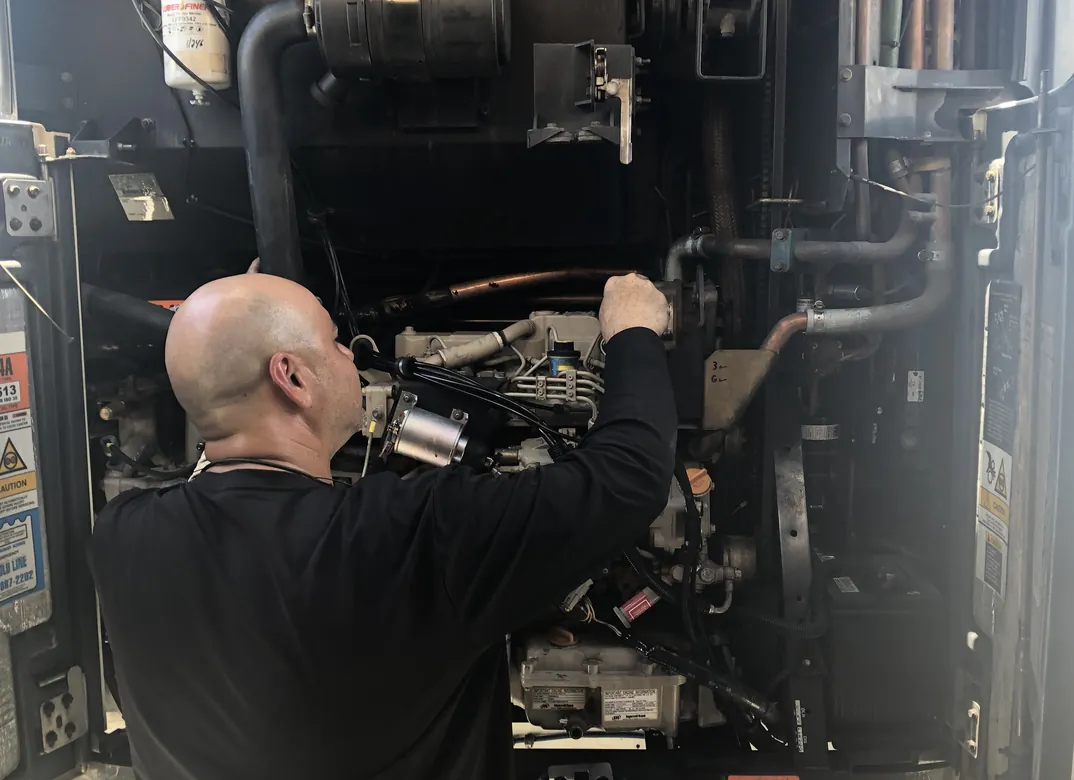 Technician repairing a transport refrigeration unit engine